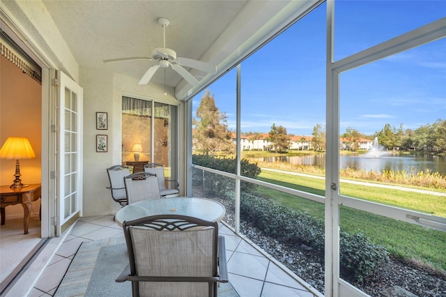 sunroom featuring ceiling fan and a water view