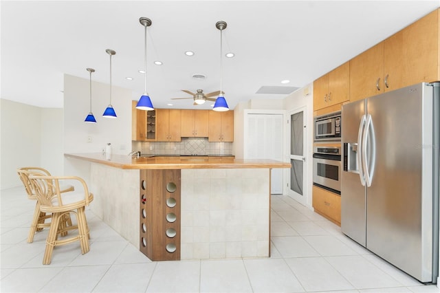 kitchen featuring ceiling fan, appliances with stainless steel finishes, decorative light fixtures, light tile patterned flooring, and kitchen peninsula