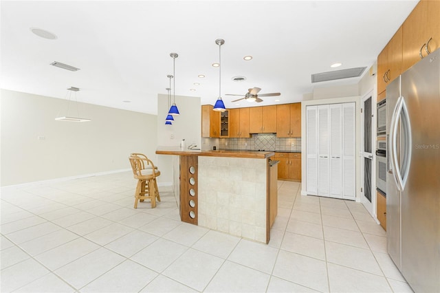 kitchen featuring tasteful backsplash, ceiling fan, pendant lighting, and appliances with stainless steel finishes