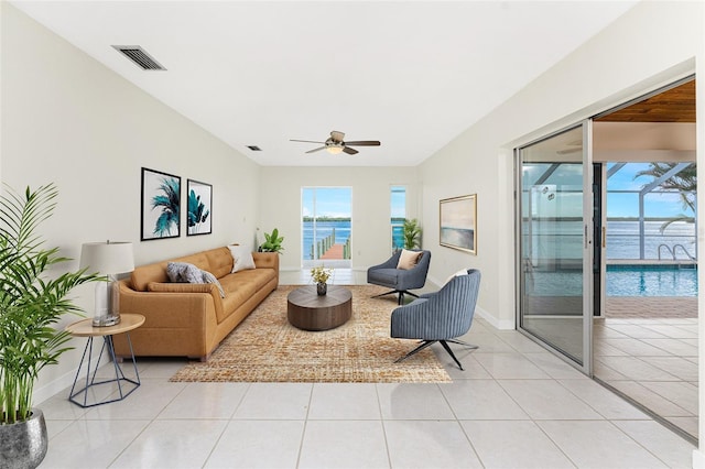 living room with light tile patterned flooring, visible vents, ceiling fan, and baseboards