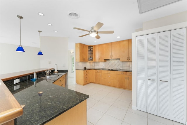 kitchen with dark stone counters, ceiling fan, sink, light tile patterned floors, and hanging light fixtures