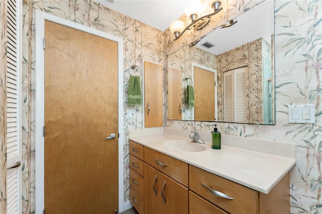 bathroom featuring a closet, visible vents, vanity, and wallpapered walls