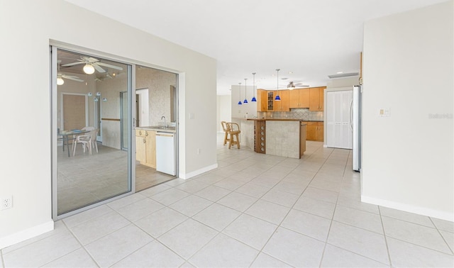 interior space featuring tasteful backsplash, freestanding refrigerator, light tile patterned floors, dishwasher, and ceiling fan