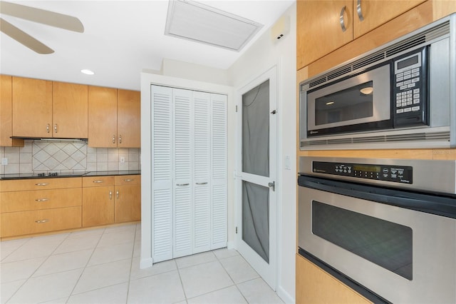 kitchen with light tile patterned floors, dark countertops, backsplash, and appliances with stainless steel finishes