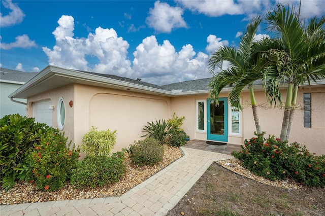 doorway to property featuring stucco siding and an attached garage