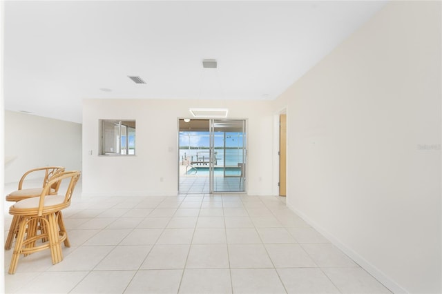 spare room with light tile patterned floors, visible vents, and baseboards