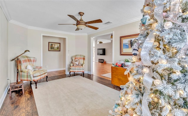 sitting room with crown molding, wood-type flooring, and ceiling fan