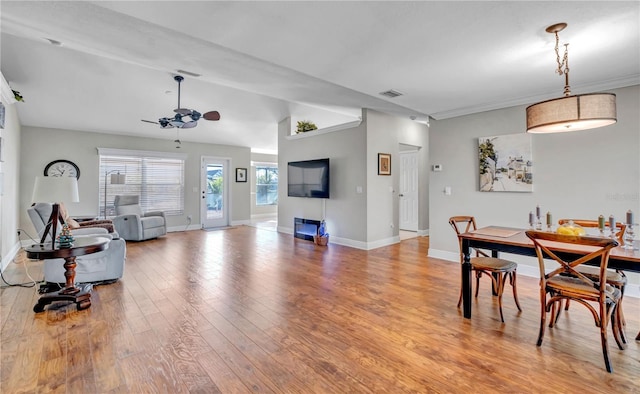 dining area featuring vaulted ceiling, ornamental molding, ceiling fan, and light wood-type flooring