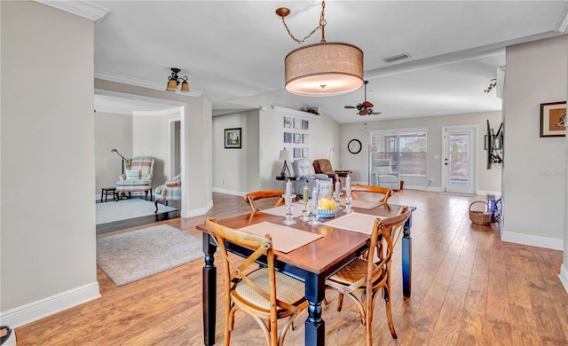 dining area with lofted ceiling, crown molding, and light hardwood / wood-style floors