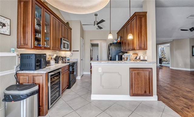 kitchen with ceiling fan, beverage cooler, light stone countertops, and black appliances