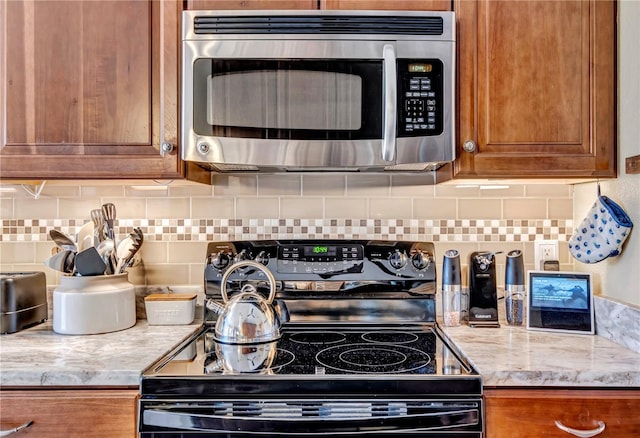 kitchen with electric range, light stone countertops, and decorative backsplash