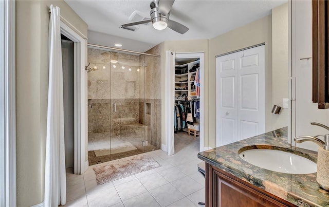 bathroom with a shower with door, vanity, tile patterned flooring, and ceiling fan