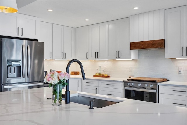 kitchen with light stone counters, white cabinetry, and appliances with stainless steel finishes