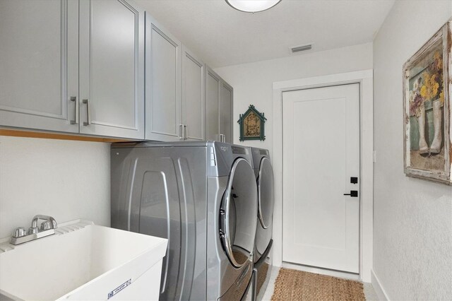 laundry area featuring separate washer and dryer, sink, and cabinets