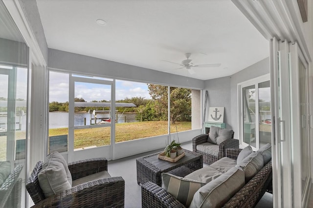 sunroom featuring ceiling fan and a water view