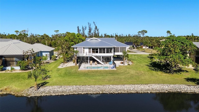 back of house featuring a lawn, a patio area, and a water view