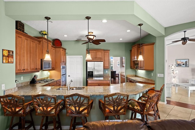 kitchen featuring kitchen peninsula, stainless steel appliances, sink, light tile patterned floors, and decorative light fixtures