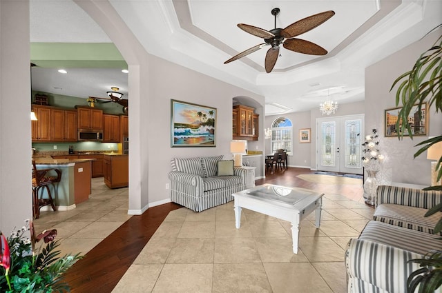 living room featuring ceiling fan with notable chandelier, french doors, light wood-type flooring, and ornamental molding