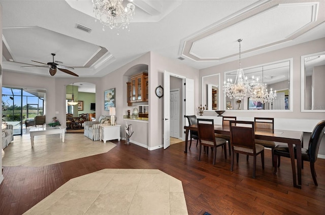 dining room featuring a tray ceiling, ceiling fan with notable chandelier, and dark hardwood / wood-style floors