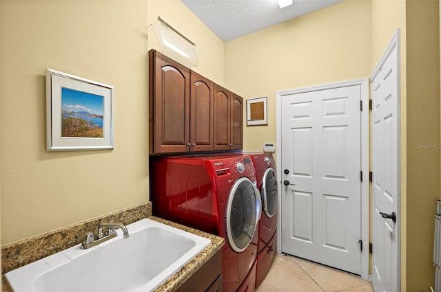 washroom featuring cabinets, a textured ceiling, sink, light tile patterned floors, and washing machine and dryer