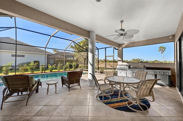 view of patio with ceiling fan, area for grilling, a lanai, and exterior kitchen