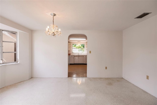 spare room featuring sink and a chandelier