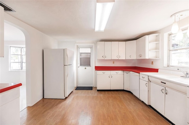 kitchen with white cabinets, light hardwood / wood-style floors, and white appliances