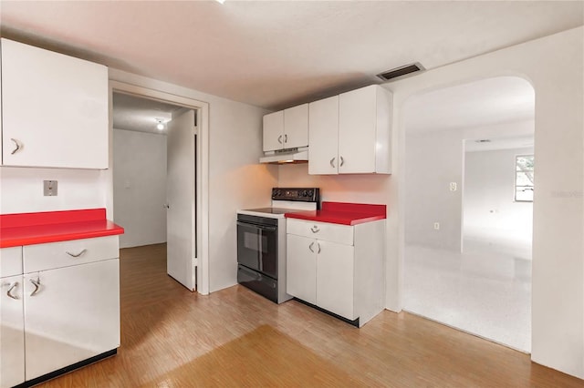 kitchen with light hardwood / wood-style flooring, white cabinetry, and black / electric stove