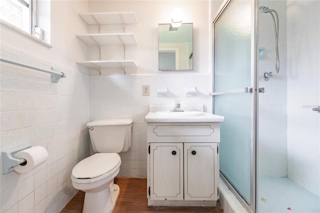 bathroom featuring hardwood / wood-style floors, vanity, a shower with door, toilet, and tile walls