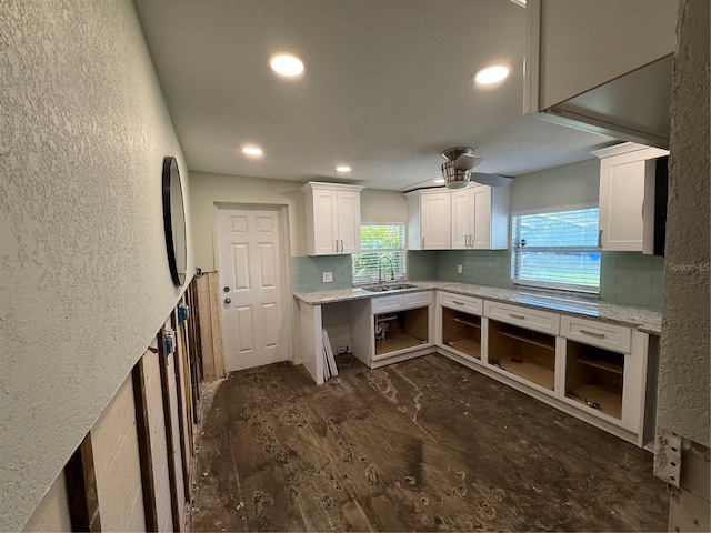 kitchen featuring light stone countertops, dark hardwood / wood-style flooring, ceiling fan, sink, and white cabinets