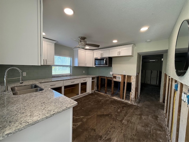 kitchen with sink, ceiling fan, light stone countertops, tasteful backsplash, and white cabinetry