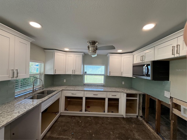 kitchen with white cabinetry, sink, and light stone counters