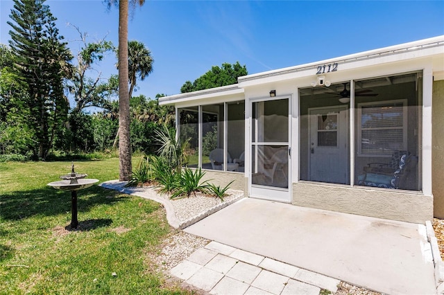 entrance to property featuring a lawn and ceiling fan