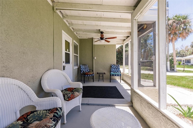 sunroom / solarium with beamed ceiling, a wealth of natural light, and ceiling fan