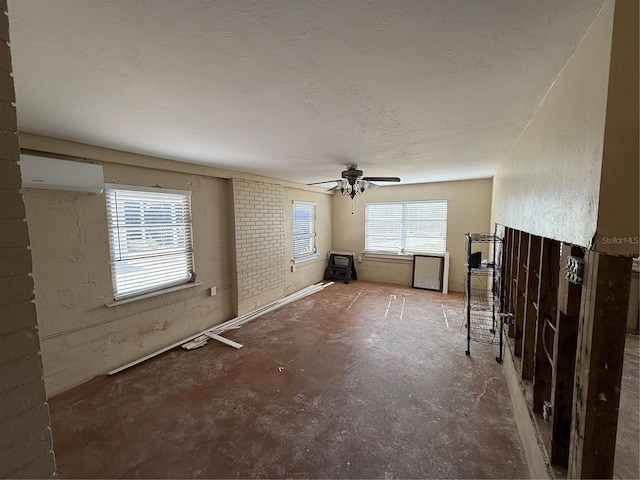 unfurnished living room with ceiling fan, concrete flooring, and a wall mounted AC