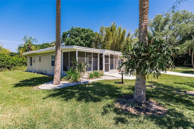 back of property with a lawn and a sunroom