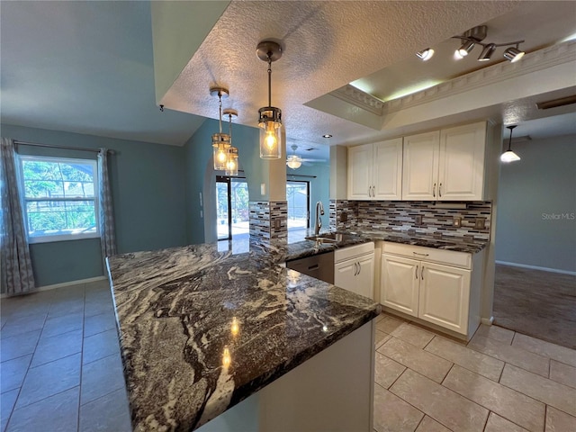 kitchen featuring kitchen peninsula, a textured ceiling, decorative light fixtures, dark stone countertops, and white cabinetry