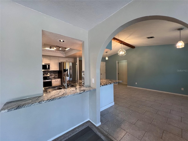 kitchen with white cabinetry, kitchen peninsula, pendant lighting, lofted ceiling, and appliances with stainless steel finishes