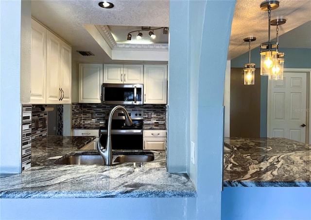 1196 Hinton St, Port Charlotte, FL 33952 - kitchen with stainless steel microwave, decorative backsplash, white cabinetry, and hanging light fixtures