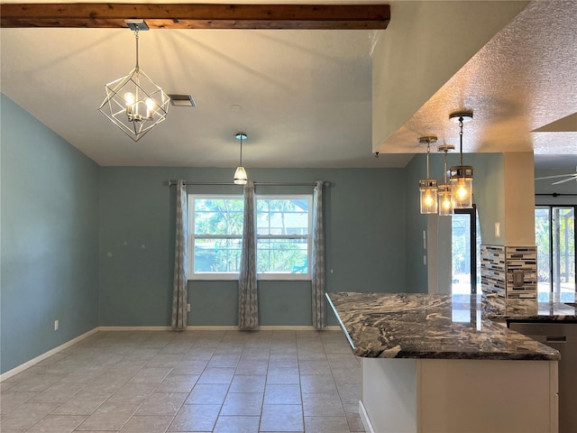 kitchen with dark stone counters, ceiling fan with notable chandelier, a textured ceiling, pendant lighting, and light tile patterned floors