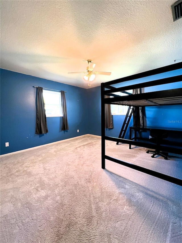 unfurnished bedroom with ceiling fan, carpet, and a textured ceiling