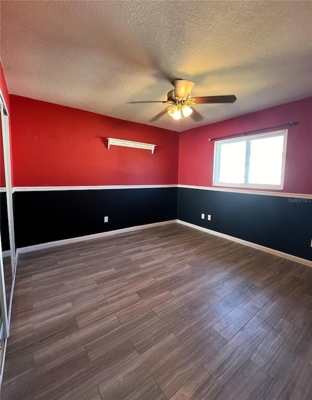 empty room featuring a textured ceiling, ceiling fan, and dark wood-type flooring