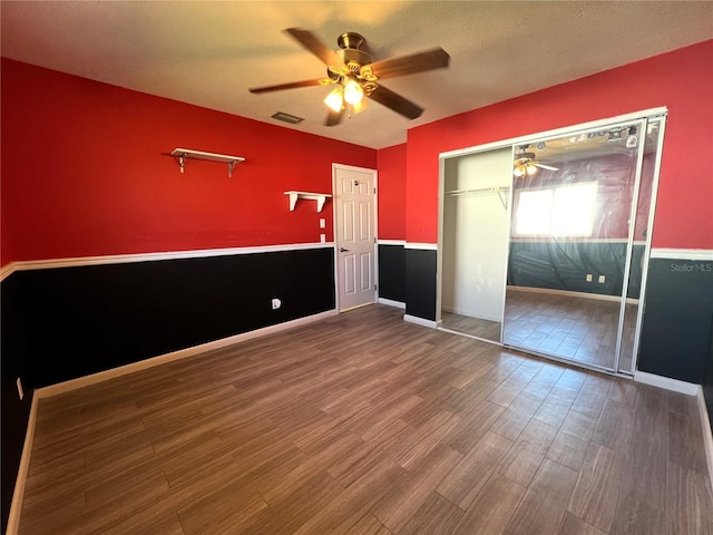 unfurnished bedroom with ceiling fan, a closet, wood-type flooring, and a textured ceiling