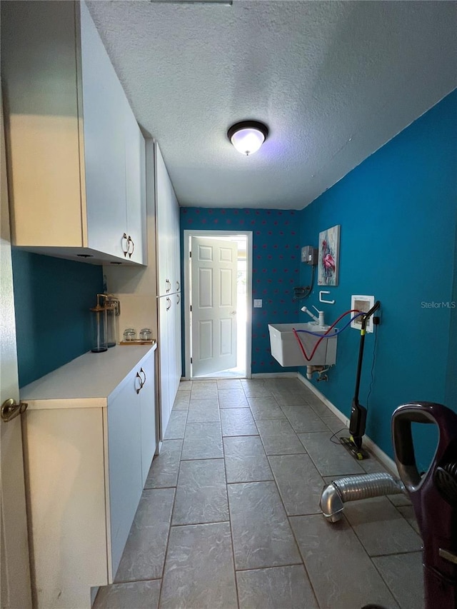 interior space featuring a textured ceiling, cabinets, sink, and hookup for a washing machine