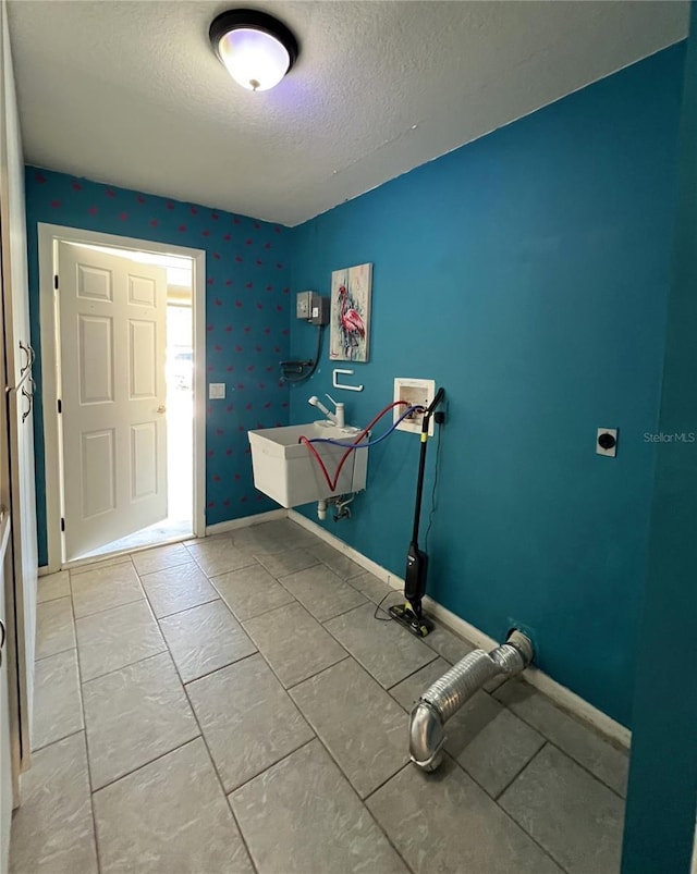 interior space featuring a textured ceiling, light tile patterned floors, and sink