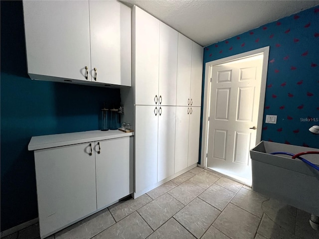 kitchen with white cabinets, light tile patterned floors, and a textured ceiling