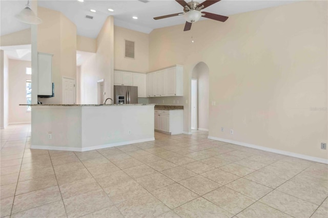 kitchen featuring ceiling fan, white cabinetry, stainless steel fridge with ice dispenser, and high vaulted ceiling