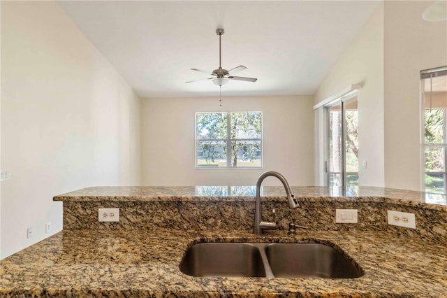 kitchen with stone counters, lofted ceiling, a healthy amount of sunlight, and sink