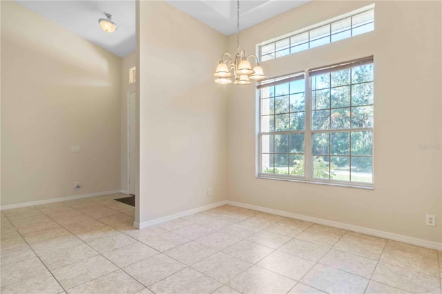 tiled empty room featuring an inviting chandelier