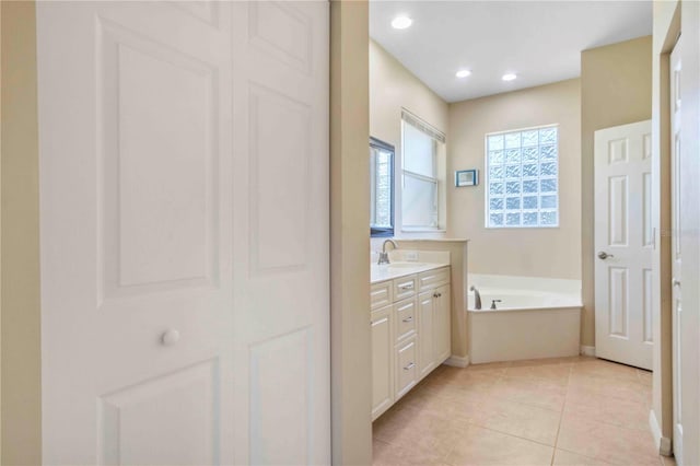 bathroom with tile patterned flooring, vanity, and a tub